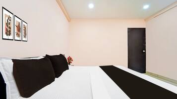 A hotel room with a bed, a black door, and three framed pictures on the wall.