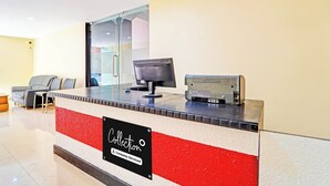 Un mostrador de recepción con un monitor de computadora, un teléfono y un letrero que indica 'Collection Company-Serviced'.