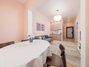 Un comedor con una mesa preparada para dos personas, un sofá y una cocina al fondo.