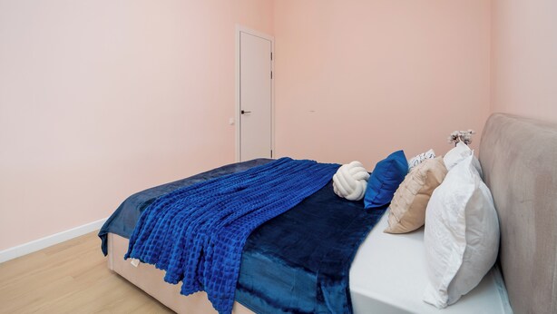 Um quarto com uma cama, uma porta e um luminário.