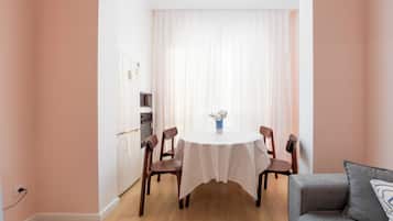 Un coin repas avec une table ronde, des chaises, un vase de fleurs et un canapé.