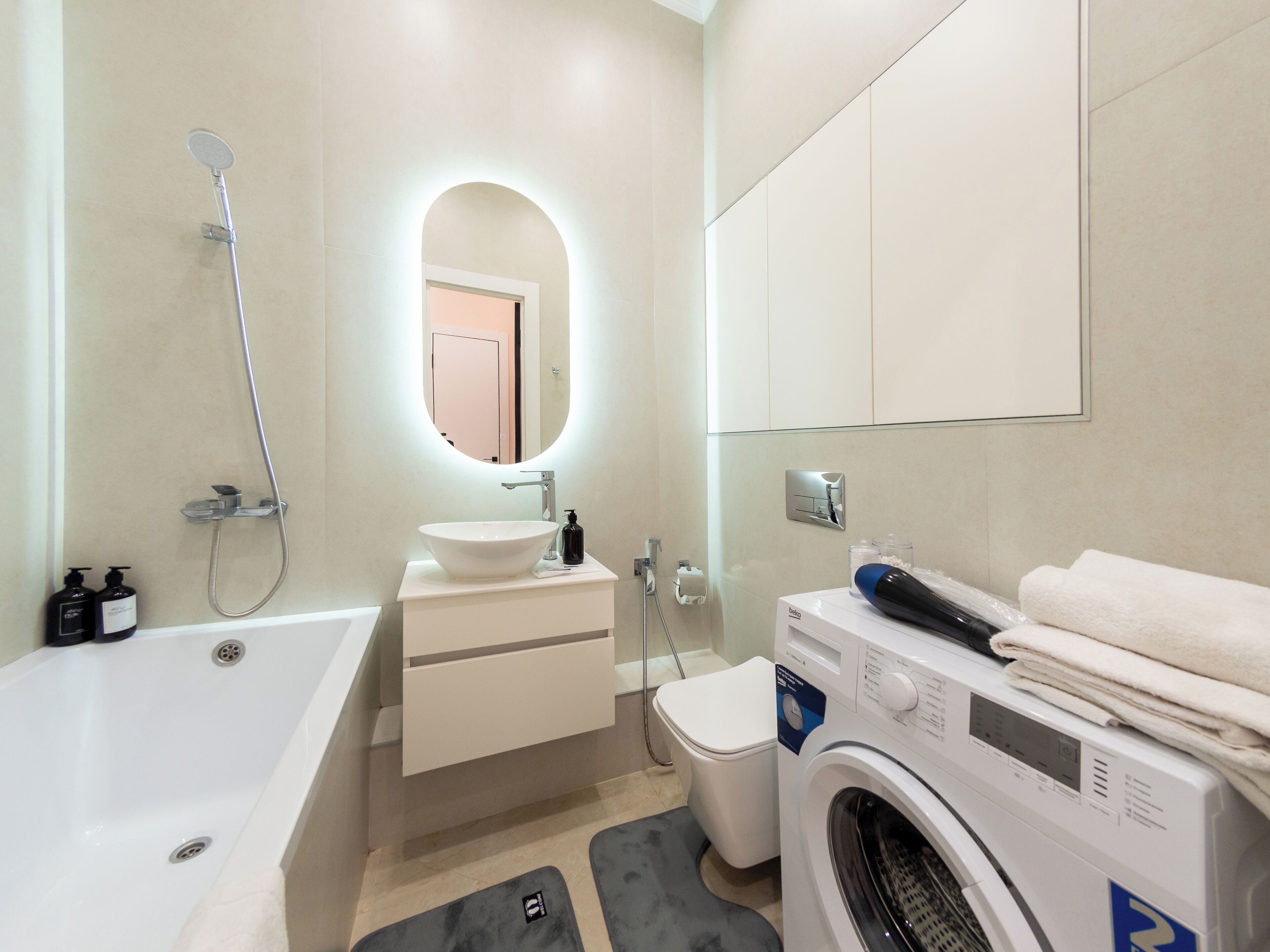 Un baño moderno con bañera, lavamanos, inodoro y lavadora.