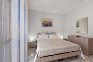 A bedroom with a bed, bedside tables, a dresser, and a mirror.