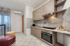 A compact kitchen with a tiled backsplash, a built-in oven, and a countertop with various appliances.