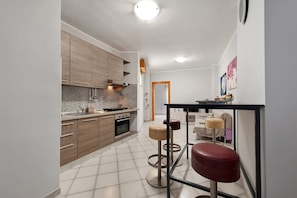 A modern kitchen with wooden cabinets, a tiled backsplash, and a dining area with stools.