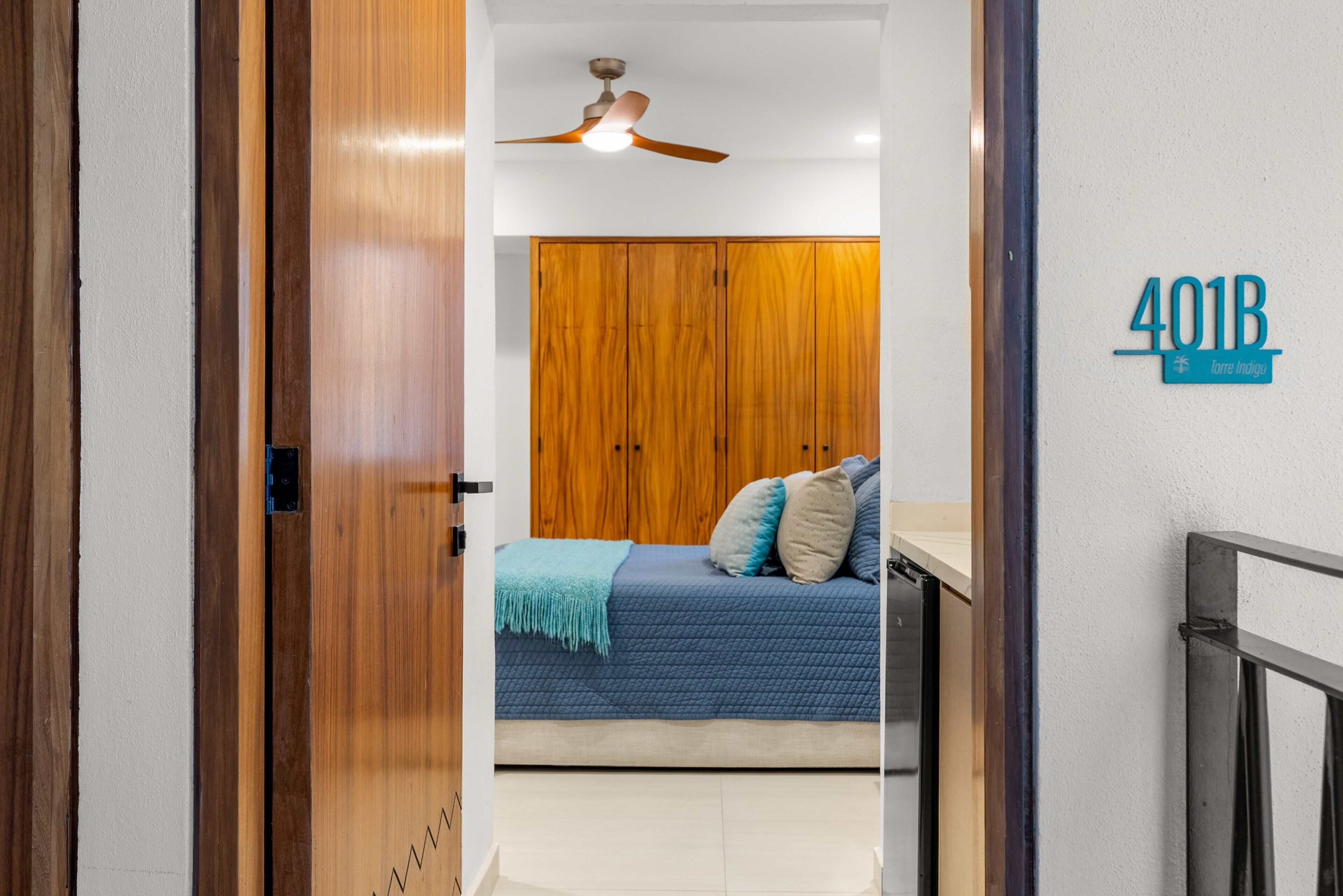 Ein Schlafzimmer mit Bett, Holzschrank, Deckenventilator und einem Schild mit der Aufschrift '401B'.