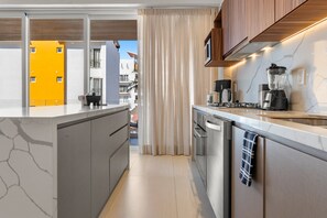A modern kitchen with a central island, stainless steel appliances, and a view of the cityscape. - 3BR condo near the ocean in Bucerías with pool, WiFi & full kitchen (Bucerias)
