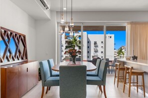 A modern dining area with a round table, blue upholstered chairs, and pendant lighting. - 3BR condo near the ocean in Bucerías with pool, WiFi & full kitchen (Bucerias)