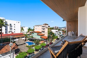 A balcony with a view of a residential area, including a swimming pool and parked cars. - Luxury 2BR Lock-Off | Rooftop Pool | Golden Zone (Nuevo Vallarta)