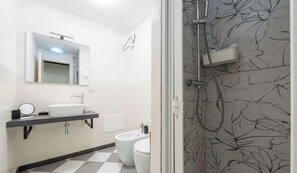 Een moderne badkamer met een wastafel, toilet en douche.