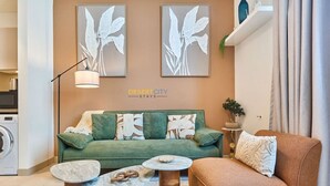 Ein Wohnzimmer mit einem grünen Sofa, zwei runden Couchtischen und einem braunen Sessel.