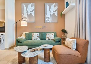 Un salón con un sofá verde, dos mesas de centro redondas y un sillón marrón.