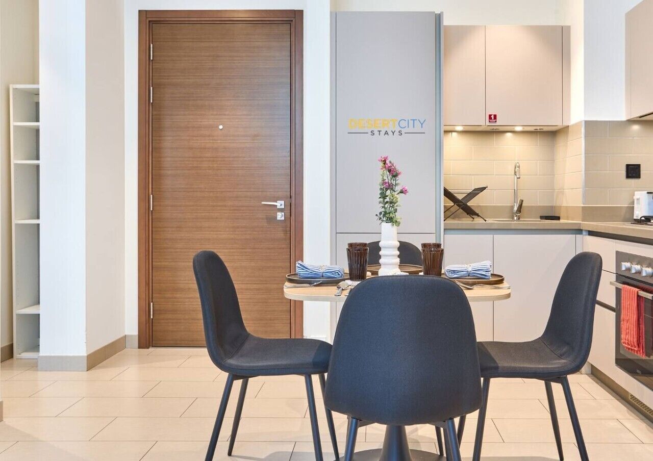 A modern kitchen with a dining area, a wooden door, and a sign for 'Desert City Stays'.