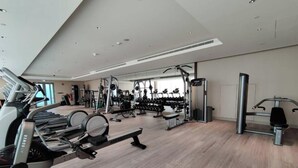 Ein modernes Fitnessstudio mit Cardiogeräten, Kurzhanteln und einer Spiegelwand.