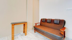 A room with a wooden table, a brown sofa, and a white wall. - Collection O Calicut Near Calicut (Kozhikode)