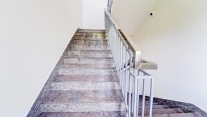 A staircase with a metal handrail and a stone floor. - Collection O Calicut Near Calicut (Kozhikode)