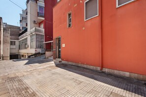 A narrow street with a red building on the right and a white building on the left.