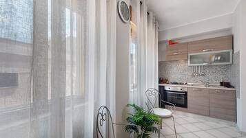 A modern kitchen with a microwave, stove, and sink. There is a dining area with a chair and a table.