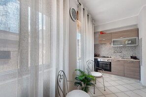 A modern kitchen with a microwave, stove, and sink. There is a dining area with a chair and a table.