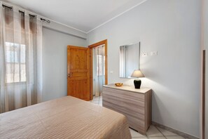 A bedroom with a bed, a dresser, a mirror, and a lamp.