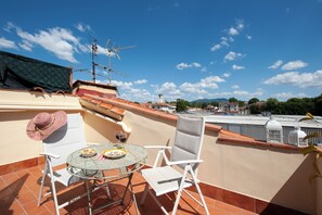 Um terraço com mesa e cadeiras, um chapéu e uma tigela de petiscos.