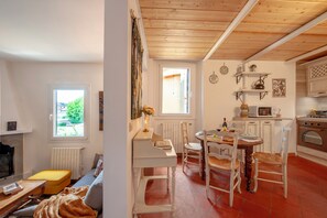 A cozy living room with a fireplace, a dining area with a wooden table and chairs, and a kitchen with white cabinets and a stove. - Terrazzino San Frediano - Flo Apartments (Florence)