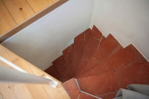 Un escalier en bois avec des marches recouvertes de carreaux rouges, qui descend.