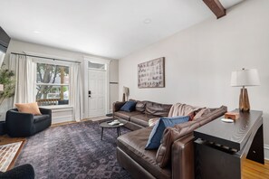 Ett modernt vardagsrum med en brun lädersoffa, ett soffbord och ett sidobord med en lampa.