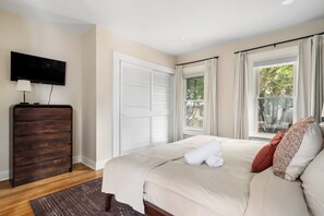 A bedroom with a bed, a dresser, a television, and a window with curtains. - Charming 2BR Retreat | Fully Equipped | Near German Village | 30+ nights (Columbus)