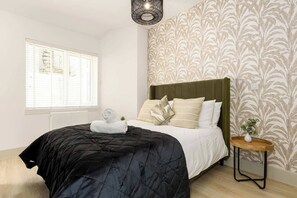 Ein Hotelzimmer mit einem Bett, einem Nachttisch mit einer Vase und einem Fenster mit Jalousien.