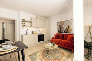 Ein zeitgemäßer Wohnraum mit Küche, Essbereich und einem roten Sofa.