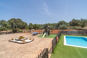 Ein Garten mit Pool, Spielbereich und Bepflanzung.