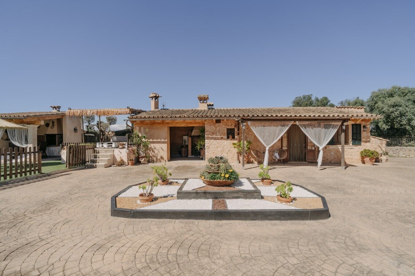 Una villa con patio, mobiliario exterior y plantas en macetas.