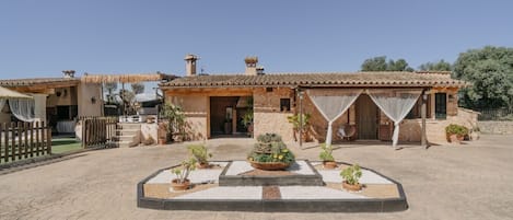 Una villa con patio, mobiliario exterior y plantas en macetas.