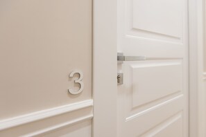 Puerta blanca con el número 3 y una cerradura.