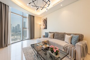 Una sala moderna con una mesa de centro de vidrio, un sofá con cojines estampados y vistas a la ciudad a través de amplios ventanales.