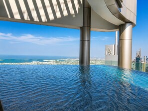 Ein Infinity-Pool auf dem Dach mit Blick auf die Stadtlandschaft und das Meer.