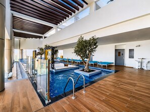 Una piscina interior con múltiples carriles, una barrera de cristal y suelo de madera.