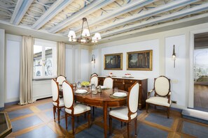 Une salle à manger avec une table en bois, six chaises, un lustre et deux tableaux accrochés au mur.