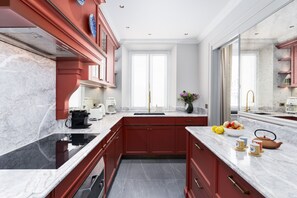 A modern kitchen with red cabinetry, a marble countertop, and a large window. - Dimora Dell’Arcangelo La Loggia (Lucca)