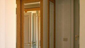 A hallway with a wooden-framed door and a mirror reflecting the interior. - Dimora Dell’Arcangelo La Loggia (Lucca)