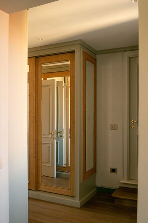 Ein Flur mit einer Holztür und einem Spiegel, der das Innere widerspiegelt.