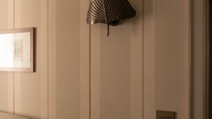 A room with a leather armchair, a wall-mounted decorative fan, and a framed picture. - Dimora Dell’Arcangelo La Loggia (Lucca)