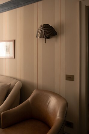 Ein Zimmer mit Ledersessel, Wandventilator und einem gerahmten Bild.
