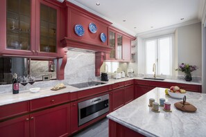 A kitchen with red cabinetry, a marble countertop, and a stainless steel oven. - Dimora Dell’Arcangelo La Loggia (Lucca)