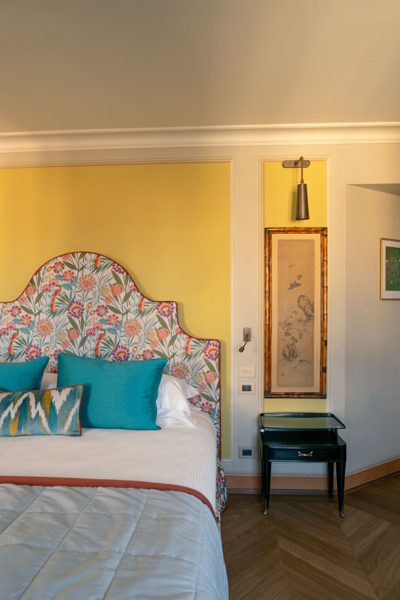A bedroom with a bed, pillows, a bedside table, and a wall-mounted light fixture.