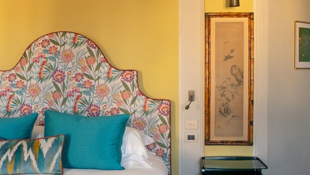 A bedroom with a bed, pillows, a bedside table, and a wall-mounted light fixture. - Dimora Dell’Arcangelo La Loggia (Lucca)