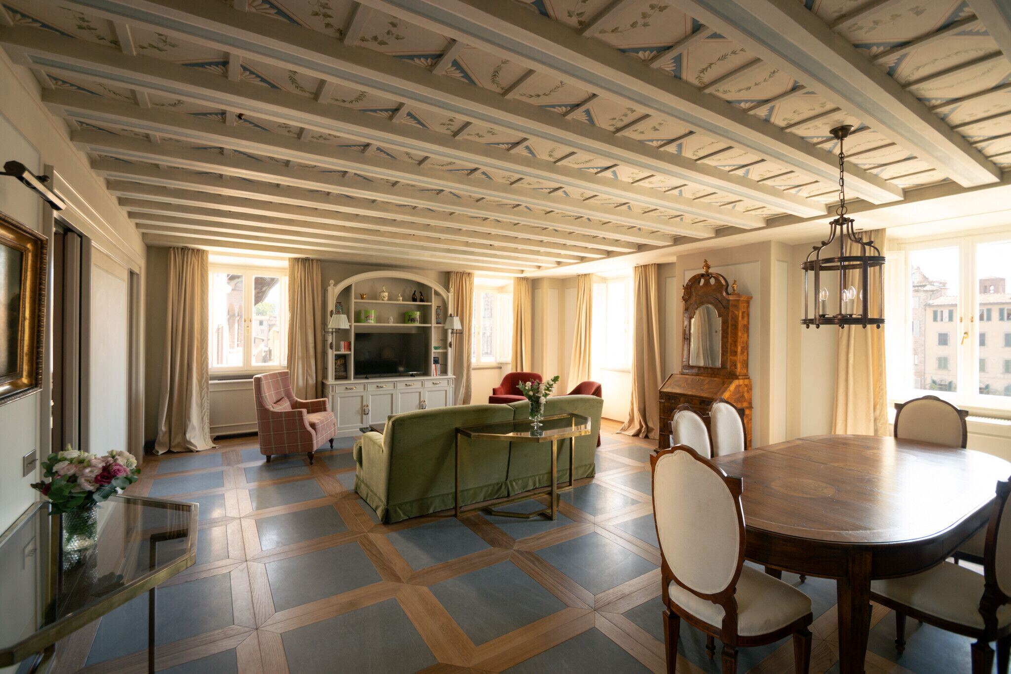 A spacious living room with a dining area, a fireplace, and a large window with curtains.