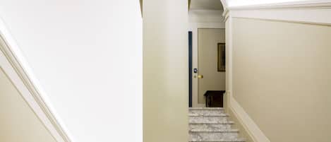 A staircase with marble steps and a central column, leading to a door at the top.