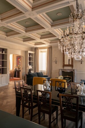 A dining area with a chandelier, a fireplace, and a view of the living room. - Dimora Dell’Arcangelo Piano Nobile (Lucca)